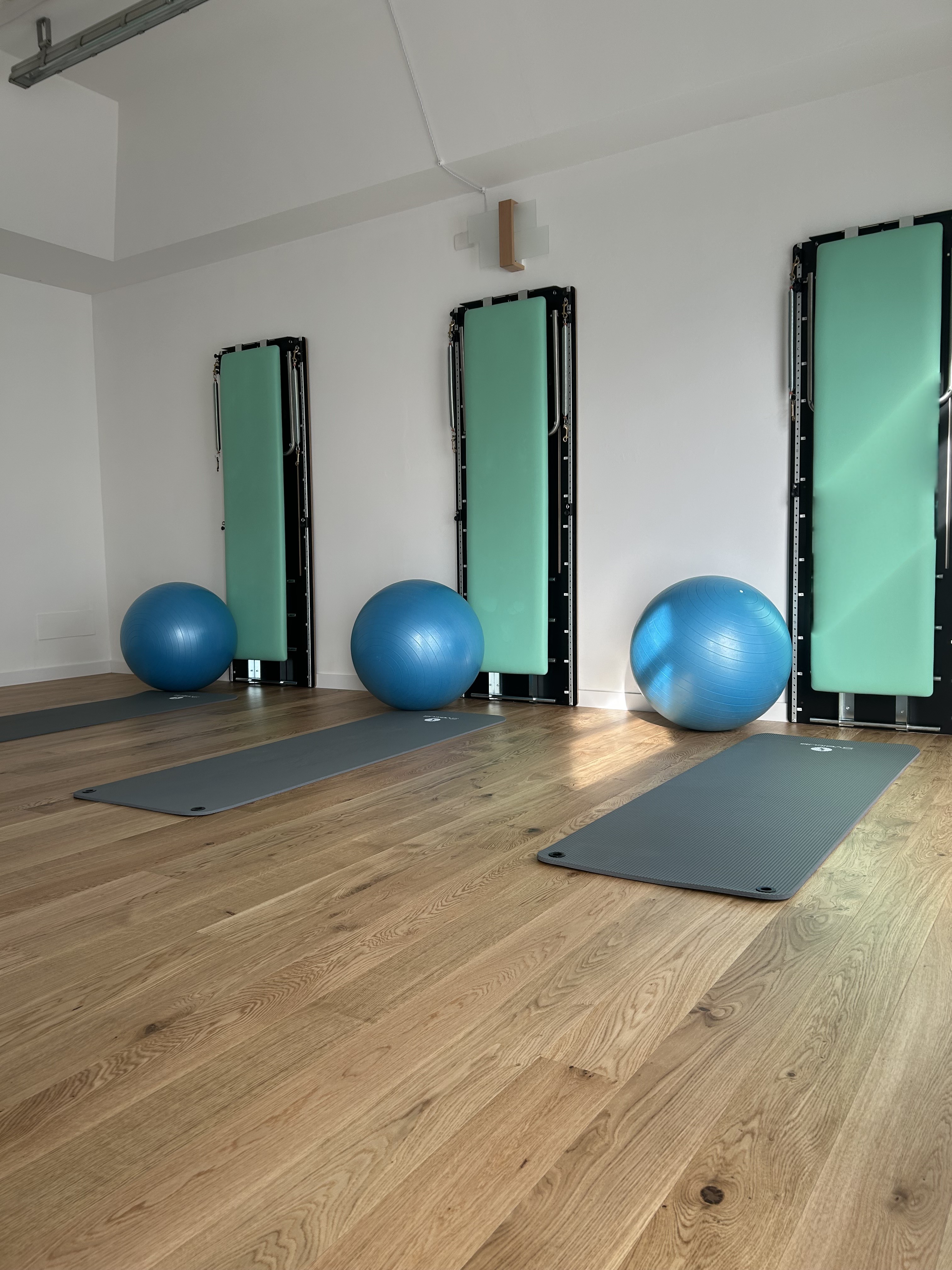 A calm, sunlit Pilates studio with reformer equipment